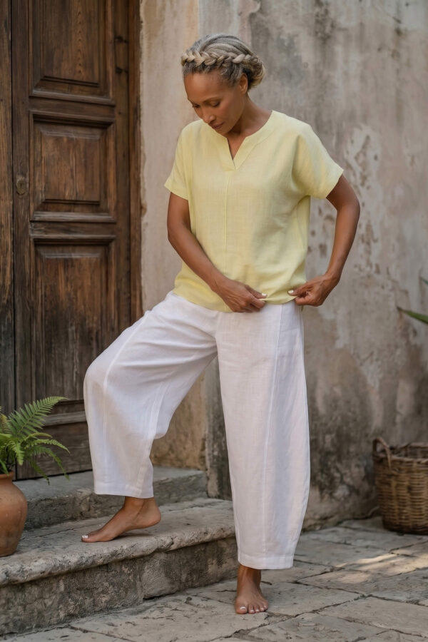 Mujer vistiendo blusa de lino amarillo vainilla y pantalón elegante de lino blanco para clima cálido