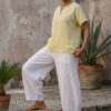Mujer vistiendo blusa de lino amarillo vainilla y pantalón elegante de lino blanco para clima cálido