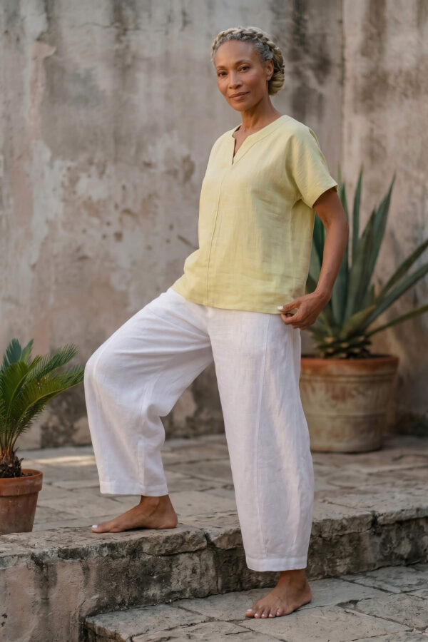 Mujer vistiendo blusa de lino amarillo vainilla y pantalón elegante de lino blanco para clima cálido
