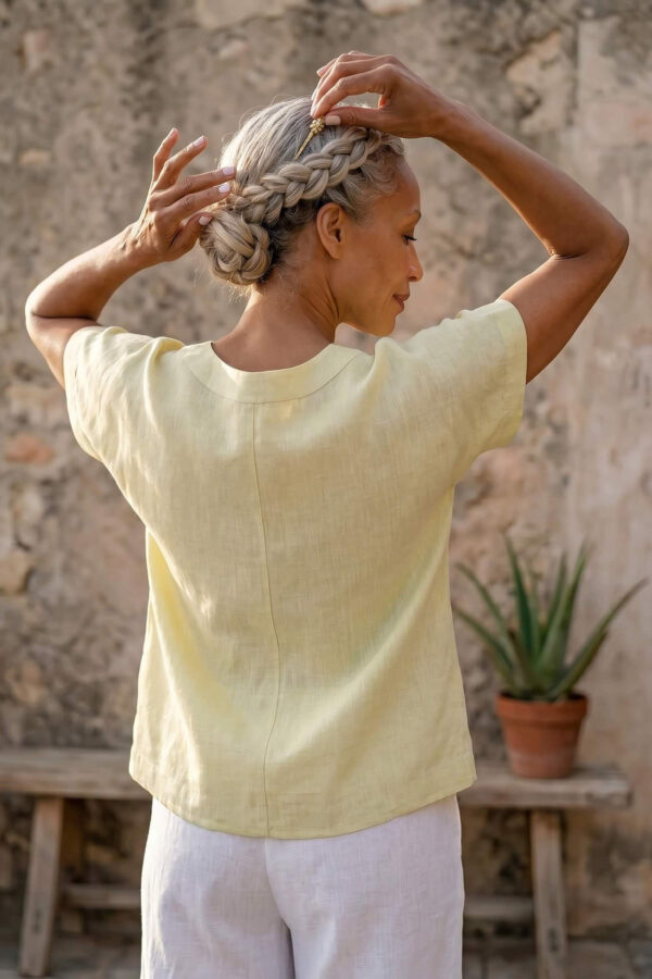 Mujer vistiendo blusa de lino amarillo vainilla y pantalón elegante de lino blanco para clima cálido