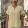 Mujer vistiendo blusa de lino amarillo vainilla y pantalón elegante de lino blanco para clima cálido