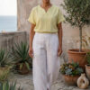 Mujer vistiendo blusa de lino amarillo vainilla y pantalón elegante de lino blanco para clima cálido