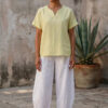 Mujer vistiendo blusa de lino amarillo vainilla y pantalón elegante de lino blanco para clima cálido