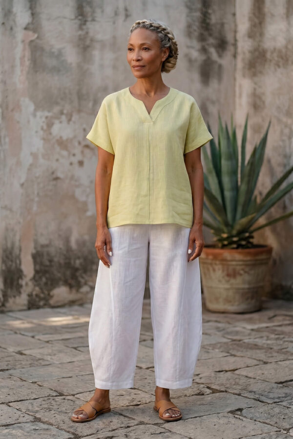 Mujer vistiendo blusa de lino amarillo vainilla y pantalón elegante de lino blanco para clima cálido