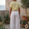 Mujer vistiendo blusa de lino amarillo vainilla y pantalón elegante de lino blanco para clima cálido