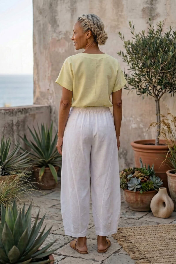 Mujer vistiendo blusa de lino amarillo vainilla y pantalón elegante de lino blanco para clima cálido