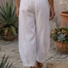 Mujer vistiendo blusa de lino amarillo vainilla y pantalón elegante de lino blanco para clima cálido