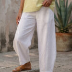 Mujer vistiendo blusa de lino amarillo vainilla y pantalón elegante de lino blanco para clima cálido