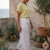 Mujer vistiendo blusa de lino amarillo vainilla y pantalón elegante de lino blanco para clima cálido