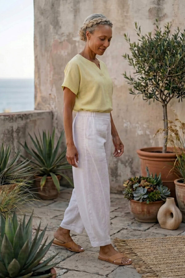 Mujer vistiendo blusa de lino amarillo vainilla y pantalón elegante de lino blanco para clima cálido