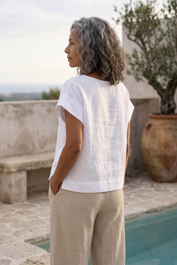 Mujer vistiendo blusa blanca de lino y pantalon de lino avena para clima calido