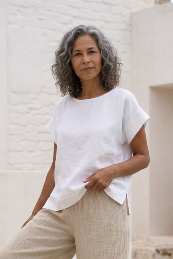 Mujer vistiendo blusa blanca de lino y pantalon de lino avena para clima calido