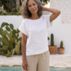 Mujer vistiendo blusa blanca de lino y pantalon de lino avena para clima calido