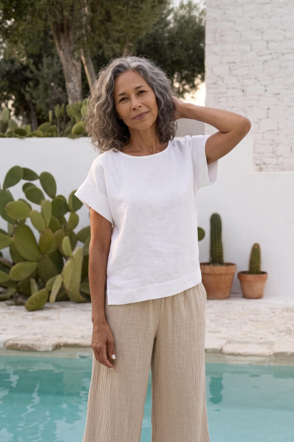 Mujer vistiendo blusa blanca de lino y pantalon de lino avena para clima calido