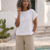 Mujer vistiendo blusa blanca de lino y pantalon de lino avena para clima calido
