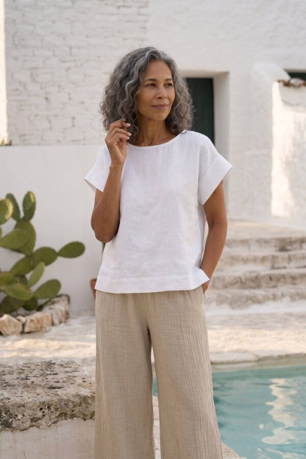 Mujer vistiendo blusa blanca de lino y pantalon de lino avena para clima calido