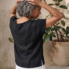 Mujer vistiendo moda atemporal con blusa de lino negro y pantalon de lino blanco