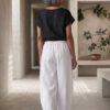 Mujer vistiendo moda atemporal con blusa de lino negro y pantalon de lino blanco