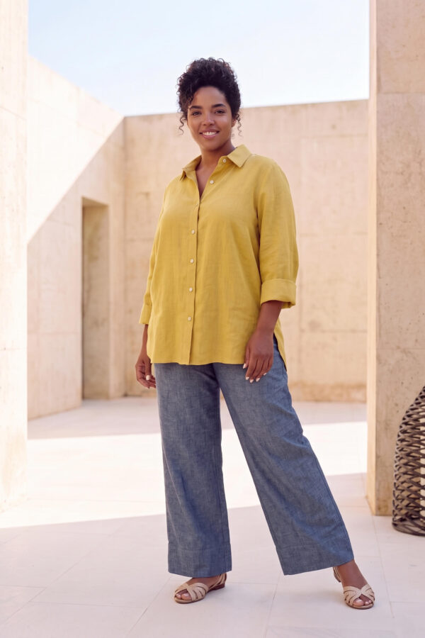 Mujer vistiendo blusa con botones de lino amarilla y pantalon estilo jeans de lino y algodón