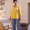 Mujer vistiendo blusa con botones de lino amarilla y pantalon estilo jeans de lino y algodón