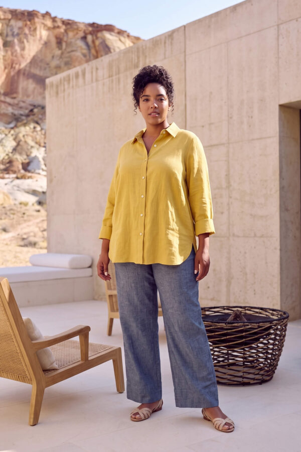 Mujer vistiendo blusa con botones de lino amarilla y pantalon estilo jeans de lino y algodón