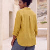 Mujer vistiendo blusa con botones de lino amarilla y pantalon estilo jeans de lino y algodón