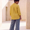 Mujer vistiendo blusa con botones de lino amarilla y pantalon estilo jeans de lino y algodón