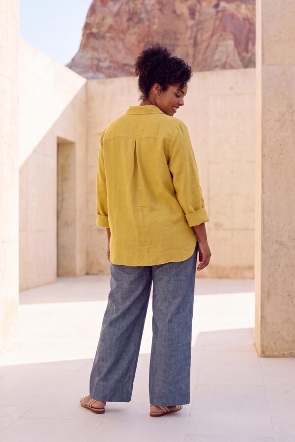 Mujer vistiendo blusa con botones de lino amarilla y pantalon estilo jeans de lino y algodón