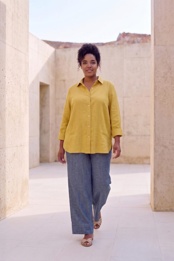 Mujer vistiendo blusa con botones de lino amarilla y pantalon estilo jeans de lino y algodón