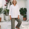 Mujer vistiendo blusa con botones de lino blanca y pantalon estilo jeans de lino y algodón verde seco