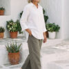Mujer vistiendo blusa con botones de lino blanca y pantalon estilo jeans de lino y algodón verde seco