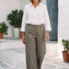 Mujer vistiendo blusa con botones de lino blanca y pantalon estilo jeans de lino y algodón verde seco