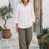 Mujer vistiendo blusa con botones de lino blanca y pantalon estilo jeans de lino y algodón verde seco