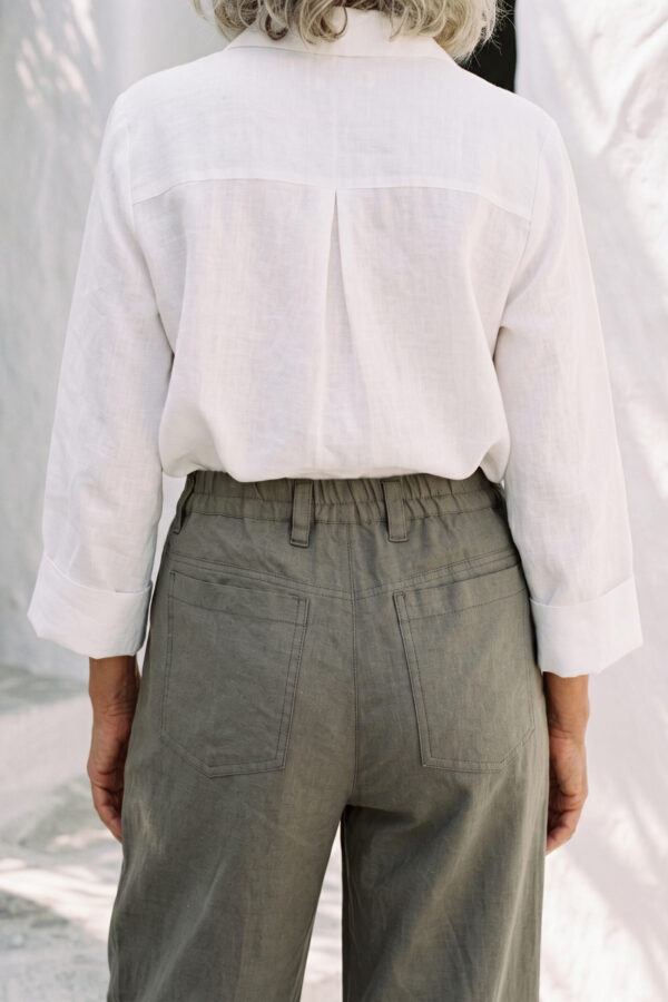 Mujer vistiendo blusa con botones de lino blanca y pantalon estilo jeans de lino y algodón verde seco