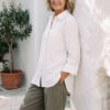 Mujer vistiendo blusa con botones de lino blanca y pantalon estilo jeans de lino y algodón verde seco