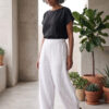 Mujer vistiendo moda atemporal con blusa de lino negro y pantalon de lino blanco