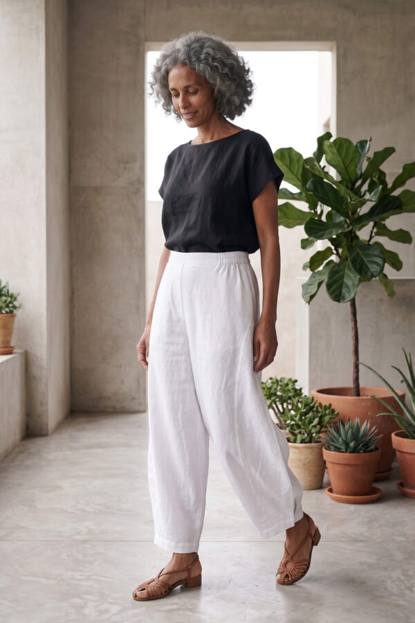 Mujer vistiendo moda atemporal con blusa de lino negro y pantalon de lino blanco