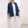 Mujer vistiendo blusa y pantalon de lino blanco y saco azul marino de fibras naturales