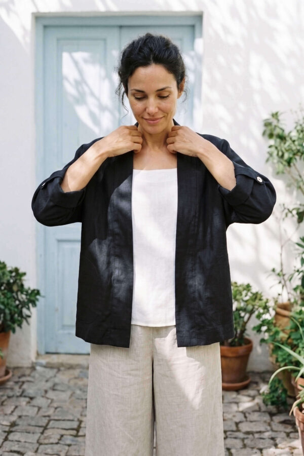 Mujer vistiendo blusa blanca, pantalon avena y saco de lino negro