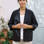 Mujer vistiendo blusa blanca, pantalon avena y saco de lino negro