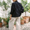 Mujer vistiendo blusa blanca, pantalon avena y saco de lino negro