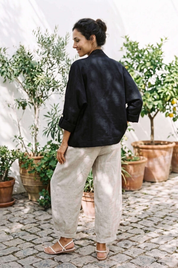 Mujer vistiendo blusa blanca, pantalon avena y saco de lino negro