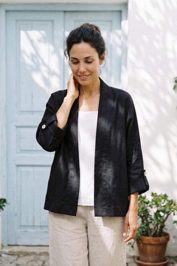 Mujer vistiendo blusa blanca, pantalon avena y saco de lino negro