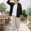 Mujer vistiendo blusa blanca, pantalon avena y saco de lino negro