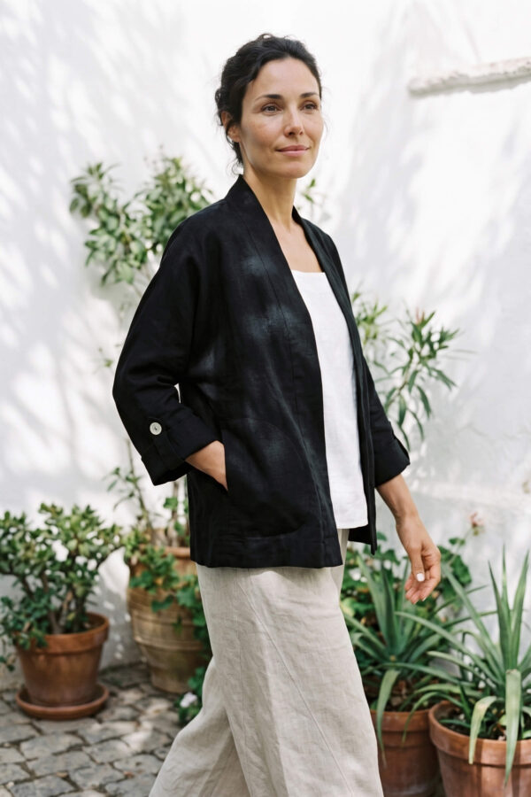 Mujer vistiendo blusa blanca, pantalon avena y saco de lino negro