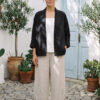 Mujer vistiendo blusa blanca, pantalon avena y saco de lino negro