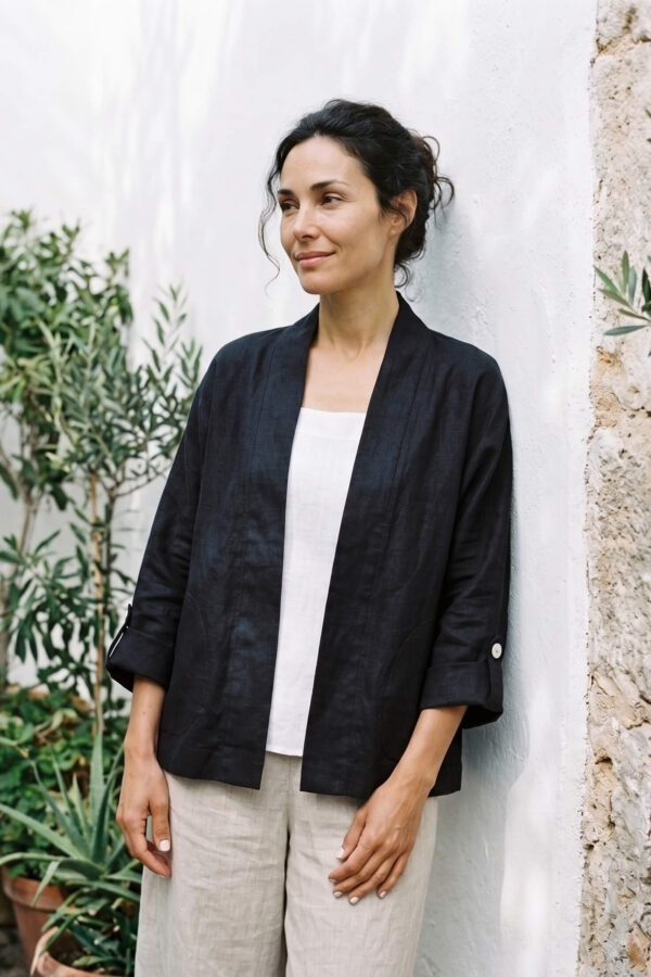 Mujer vistiendo blusa blanca, pantalon avena y saco de lino negro