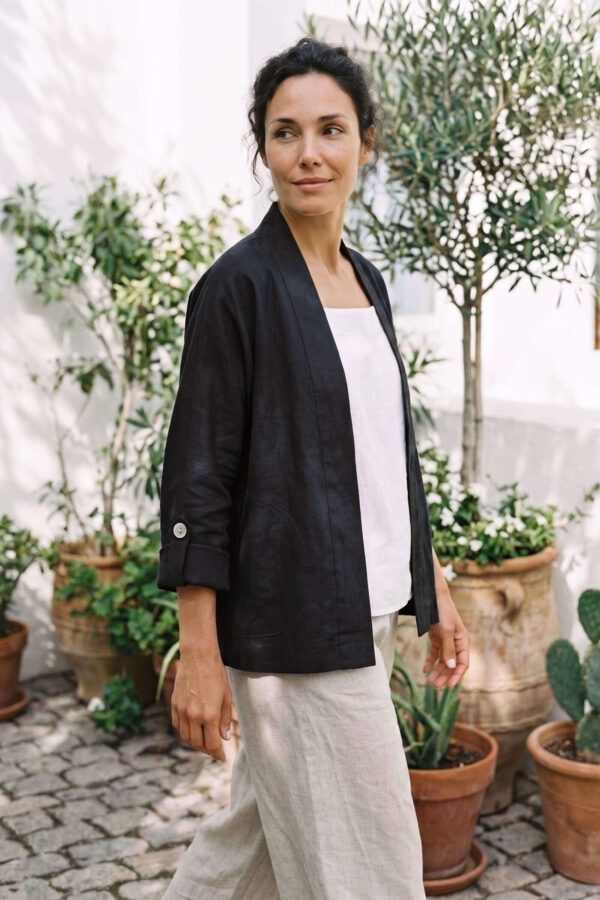 Mujer vistiendo blusa blanca, pantalon avena y saco de lino negro
