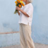 Mujer vistiendo blusa manga amplia de lino blanca y pantalon color avena