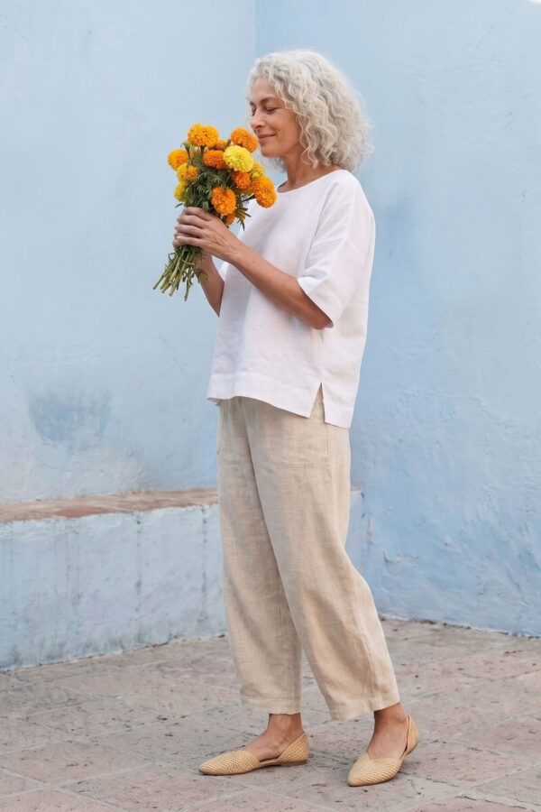 Mujer vistiendo blusa manga amplia de lino blanca y pantalon color avena